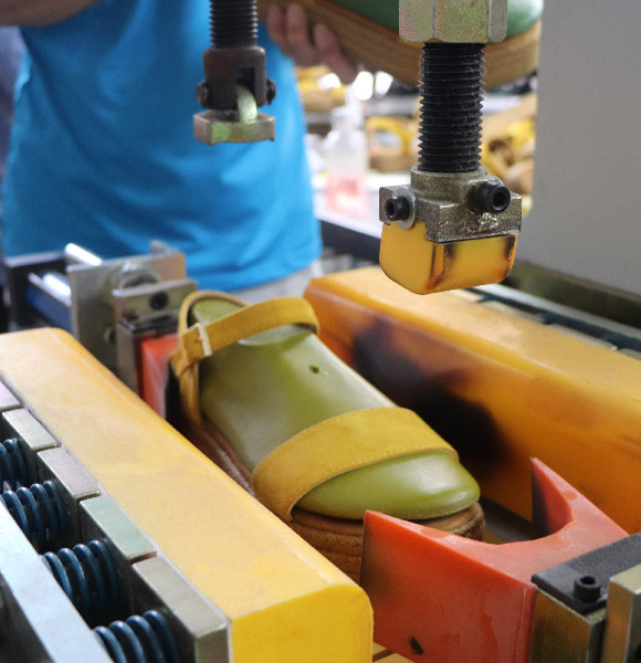 A worker pulls the upper onto the last and uses a stretching machine to fit it properly to the last.