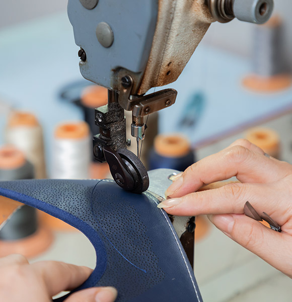 A worker meticulously sewing the upper of a shoe.