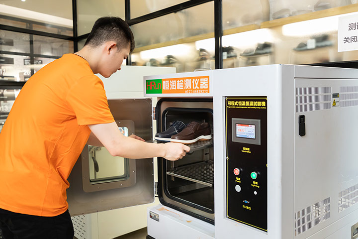 An employee uses a machine to perform Constant Temperature and Humidity Test on shoes.