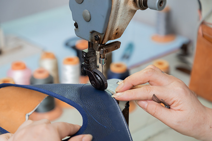 A worker meticulously sewing the upper of a shoe.