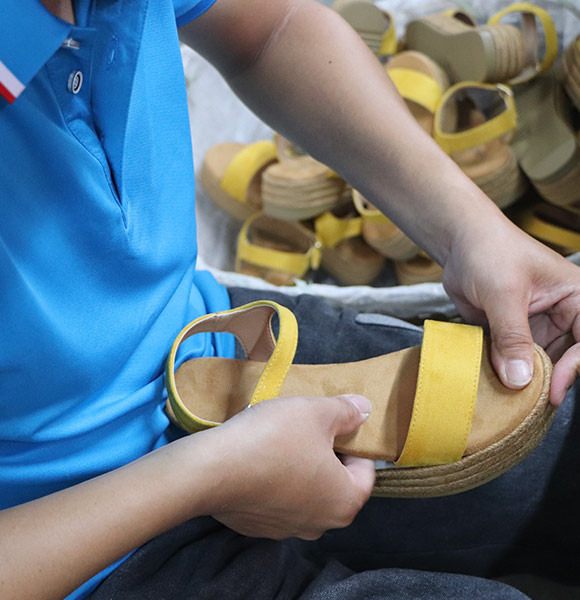 A worker meticulously glues the sole and upper of a shoe.