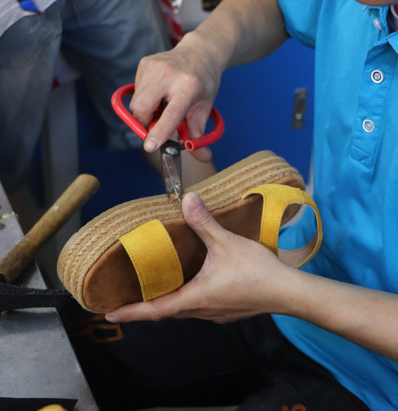 A worker trimming the sole of a shoe.